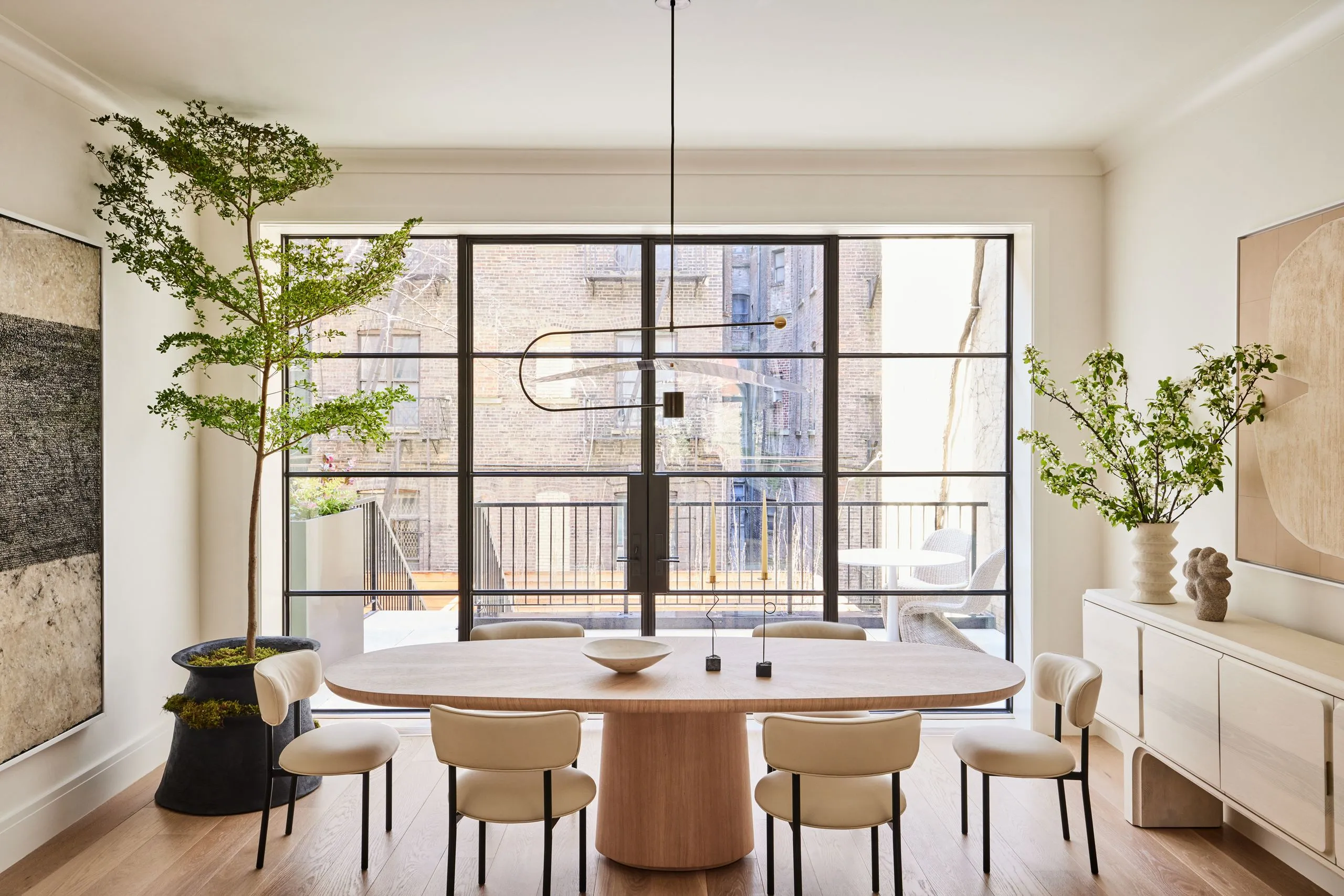 Minimalist dining room in a Jayanagar Bengaluru residence with a long stone-topped table, sculptural chairs and a linear pendant fixture