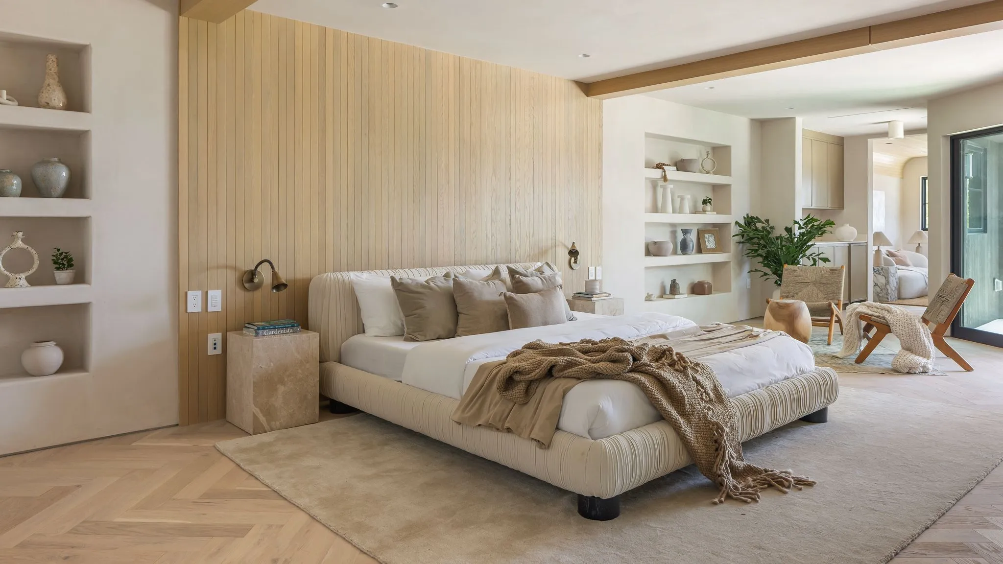 Master bedroom of a Devanahalli farm villa near Bengaluru with a timber-clad headboard wall, layered warm lighting and garden views